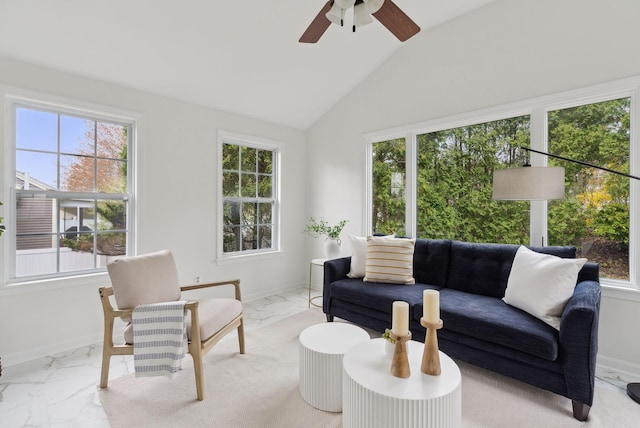 living area featuring marble look tile flooring, healthy amount of natural light, a ceiling fan, and high vaulted ceiling