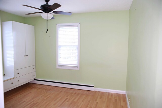 165 Pleasant Ave, Madawaska, ME 04756 - unfurnished bedroom featuring a baseboard heating unit, light wood-type flooring, multiple windows, and baseboards