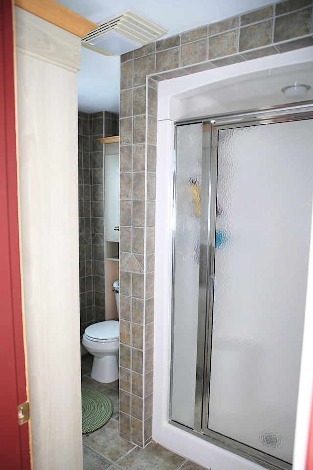 165 Pleasant Ave, Madawaska, ME 04756 - bathroom with tile walls, a shower stall, tile patterned floors, and toilet