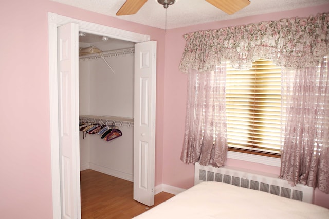 165 Pleasant Ave, Madawaska, ME 04756 - bedroom featuring radiator, a closet, wood finished floors, baseboards, and a ceiling fan