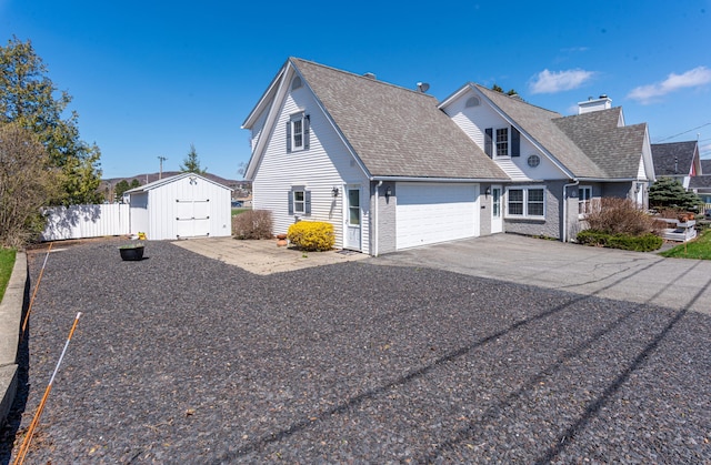 165 Pleasant Ave, Madawaska, ME 04756 - view of home's exterior featuring a storage unit, fence, an attached garage, asphalt driveway, and roof with shingles