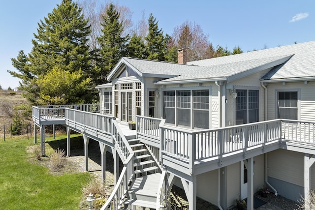 rear view of property featuring a wooden deck, a chimney, a shingled roof, a yard, and stairway