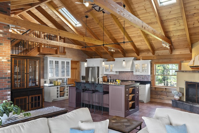 living area with wood ceiling, high vaulted ceiling, a skylight, and beamed ceiling