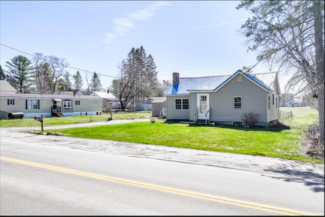 21 Exeter Rd, Corinna, ME 04928 - view of front of house featuring a chimney, entry steps, a front lawn, and metal roof