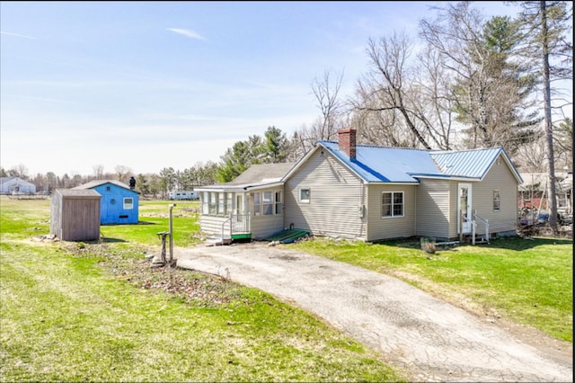 21 Exeter Rd, Corinna, ME 04928 - rear view of house with a chimney, a yard, a storage unit, an outbuilding, and driveway