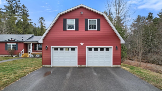 garage featuring aphalt driveway and covered porch