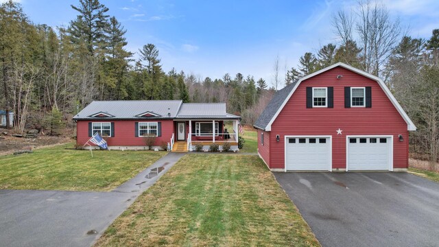 view of front of home with a detached garage, a porch, a front lawn, a gambrel roof, and driveway