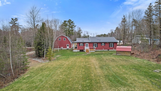 rear view of property featuring a yard and an outbuilding