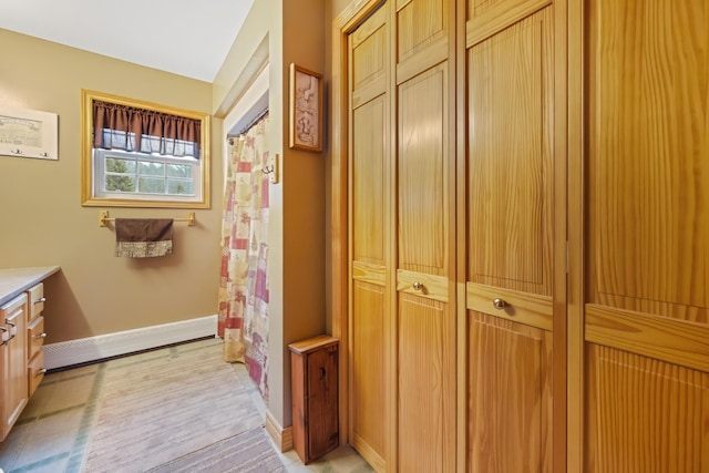 full bath with a shower with shower curtain, vanity, and baseboards