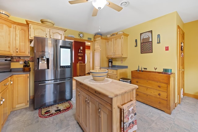 kitchen with ceiling fan, light brown cabinets, stainless steel fridge, and stone finish flooring