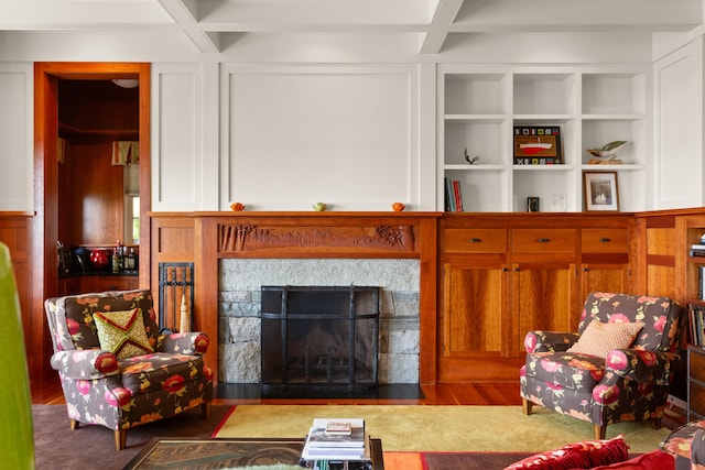 living area featuring a fireplace with flush hearth, wood finished floors, beamed ceiling, and coffered ceiling