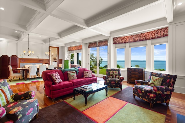 living area with wood finished floors, a chandelier, a water view, and a decorative wall