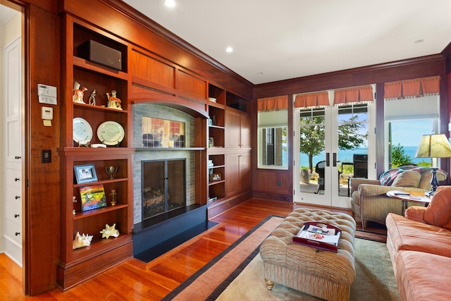 living room with crown molding, french doors, wood finished floors, and built in features