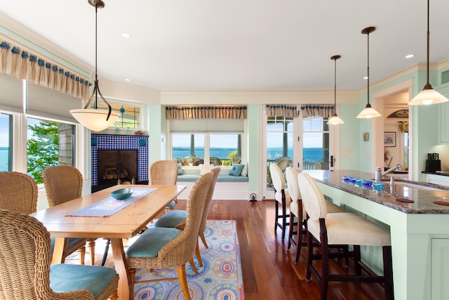 dining room with recessed lighting, plenty of natural light, a tiled fireplace, and dark wood-style floors