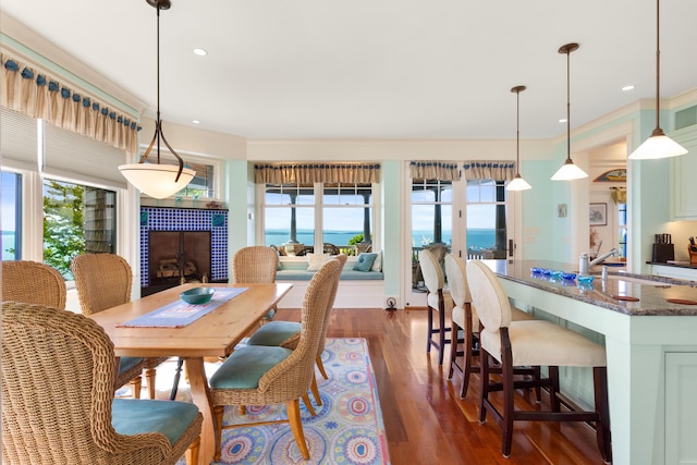 dining area with dark wood-type flooring, a tiled fireplace, and recessed lighting