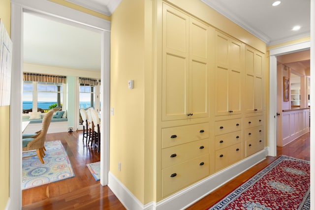corridor featuring baseboards, crown molding, and wood finished floors