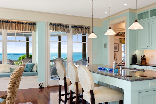 dining space featuring recessed lighting, dark wood-type flooring, and a water view
