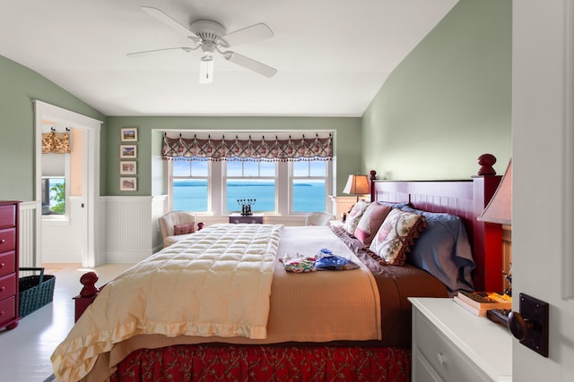 bedroom featuring lofted ceiling, a ceiling fan, wood finished floors, and wainscoting