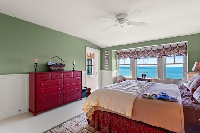 bedroom featuring vaulted ceiling, a wainscoted wall, and a ceiling fan