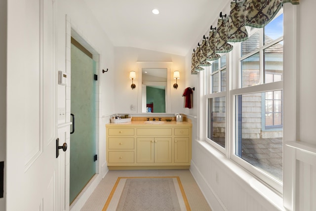 bathroom with tile patterned flooring, vaulted ceiling, vanity, baseboards, and a stall shower