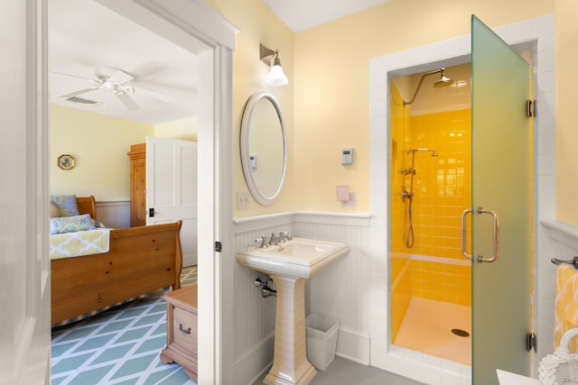 ensuite bathroom with a wainscoted wall, ensuite bathroom, ceiling fan, and a stall shower