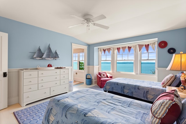 bedroom with lofted ceiling, a wainscoted wall, and ceiling fan