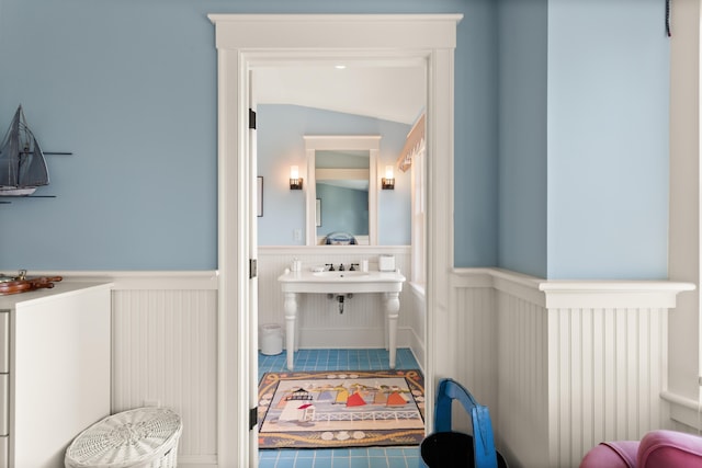bathroom featuring wainscoting, tile patterned flooring, and a decorative wall