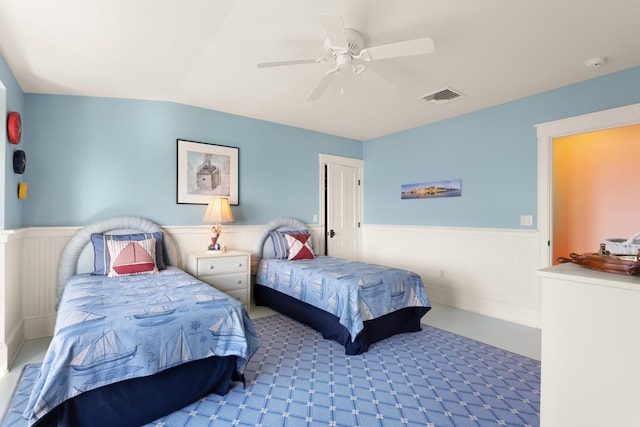 bedroom featuring wainscoting, a ceiling fan, visible vents, and carpet floors