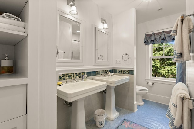 bathroom with toilet, tile patterned flooring, and tile walls
