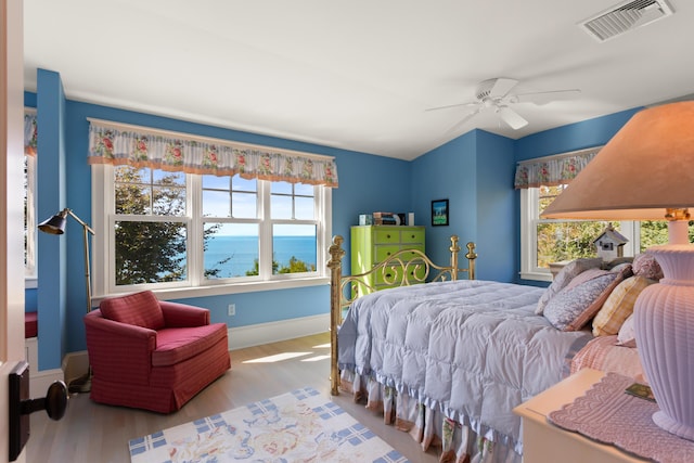 bedroom featuring baseboards, wood finished floors, visible vents, and a ceiling fan
