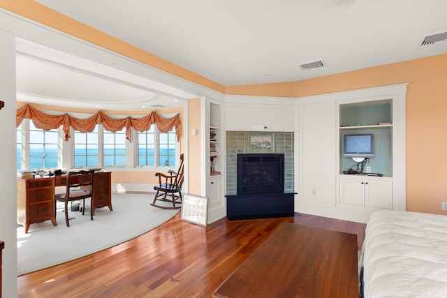 bedroom featuring wood finished floors, visible vents, and a tile fireplace
