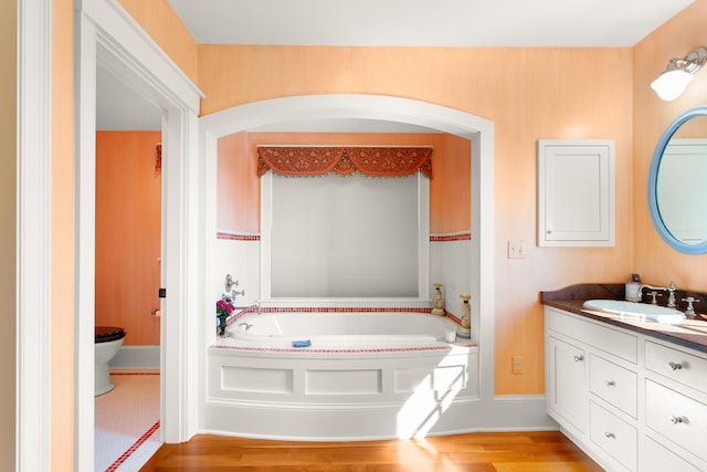 full bath featuring a garden tub, toilet, vanity, and wood finished floors