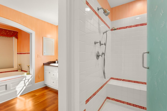 bathroom featuring a bath, a shower stall, vanity, and wood finished floors