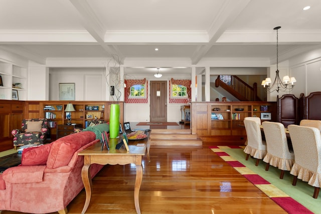 recreation room with wood finished floors, beam ceiling, a notable chandelier, and crown molding