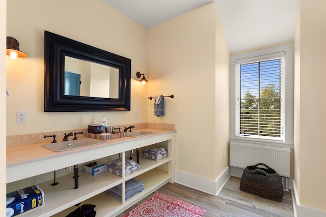 bathroom featuring radiator heating unit, vanity, baseboards, and wood finished floors