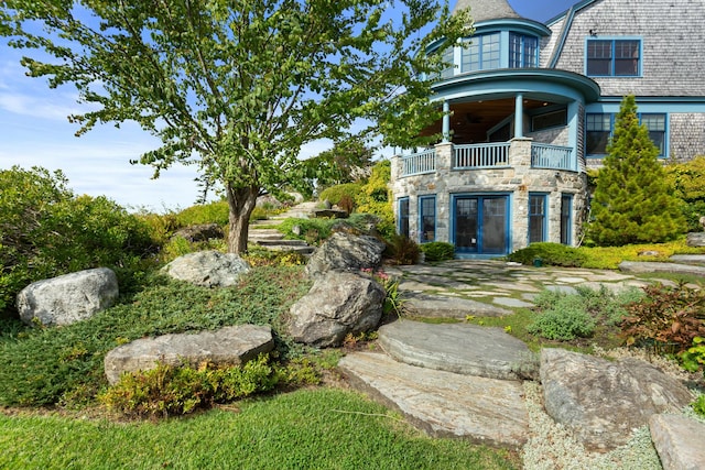 view of yard with french doors and a balcony