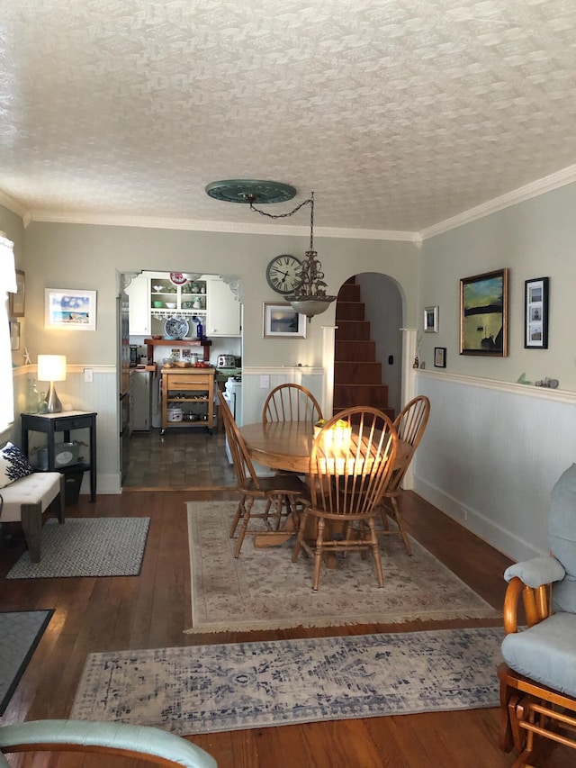 57 Salmond St, Belfast, ME 04915 - dining space with a wainscoted wall, arched walkways, ornamental molding, dark wood-style flooring, and a textured ceiling