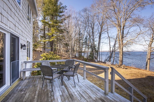 deck with outdoor dining space and a water view