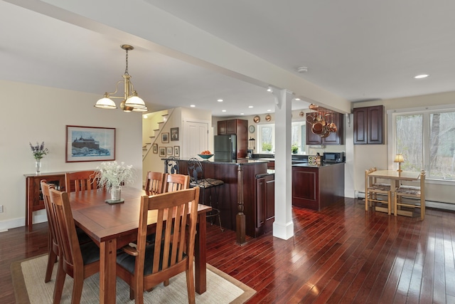 dining space with plenty of natural light, baseboard heating, dark wood-style floors, and stairs