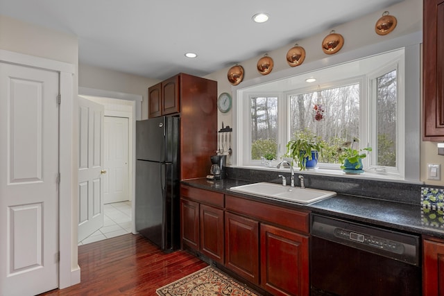 kitchen featuring black appliances, dark countertops, dark brown cabinets, and a sink