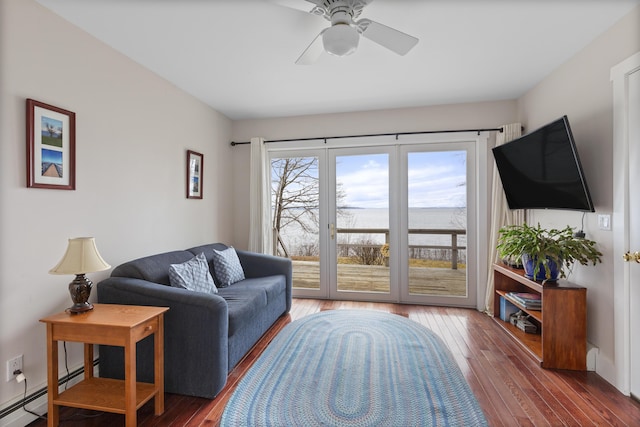 living area with baseboard heating, hardwood / wood-style flooring, and a ceiling fan