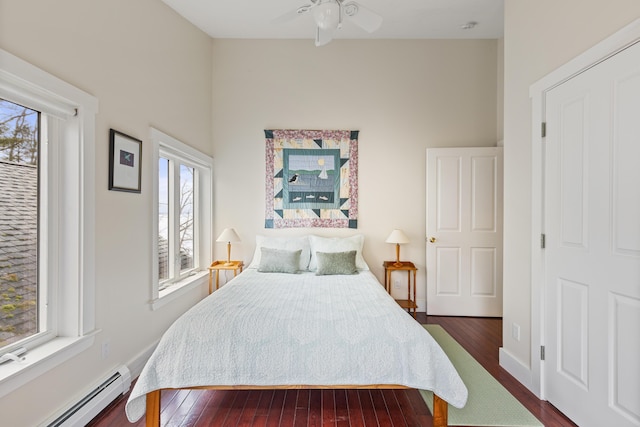 bedroom with a baseboard radiator, a ceiling fan, and dark wood-type flooring
