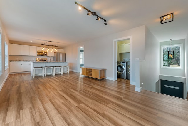 56 Old Kings Hwy, Ogunquit, ME 03907 - living area with track lighting, washing machine and clothes dryer, baseboards, and light wood finished floors
