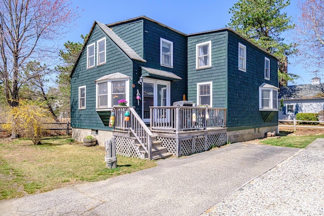 view of front of property featuring fence, a wooden deck, and a front lawn