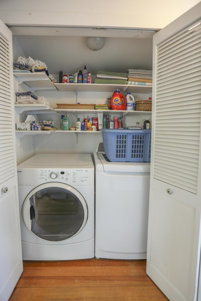 clothes washing area with light wood finished floors, washing machine and dryer, and laundry area