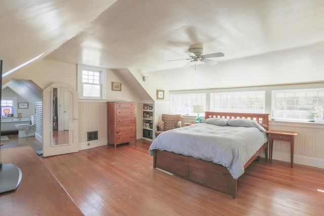 bedroom featuring visible vents, baseboards, hardwood / wood-style flooring, ensuite bath, and lofted ceiling