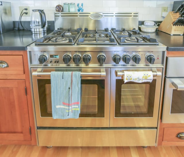 room details with double oven range, brown cabinetry, and decorative backsplash