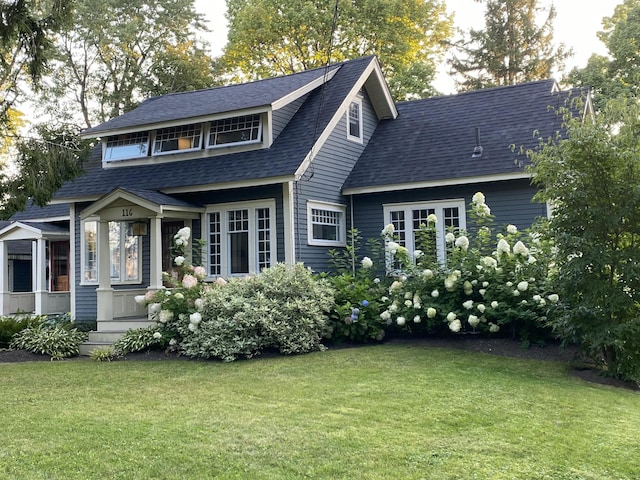 rear view of property with a lawn and roof with shingles