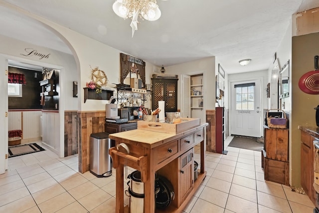 kitchen featuring a wainscoted wall, arched walkways, butcher block countertops, and light tile patterned floors