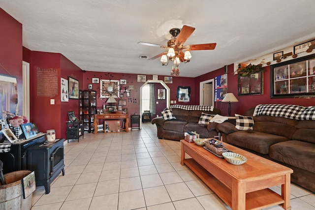 living area featuring ceiling fan, a wood stove, and light tile patterned floors